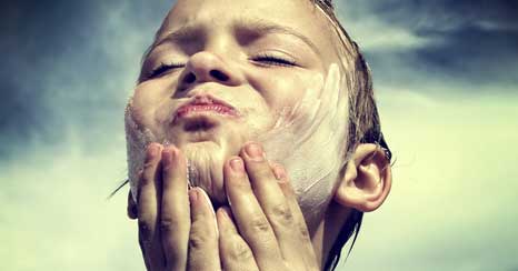 Young boy applying sunscreen to his face
