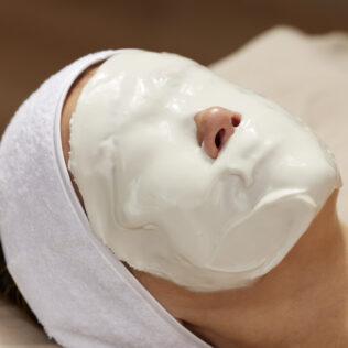 patient resting with thick white calming mask on face during facial treatment